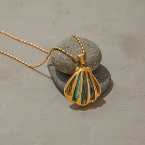 Detail view of shell-shaped gold necklace with abalone inlay on grey stones