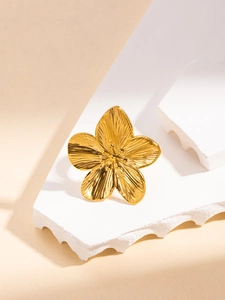 Macro detail of golden flower ring with radial textures on a white stone base