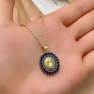 Golden Virgin Mary pendant necklace with deep blue zircon stones held in hand