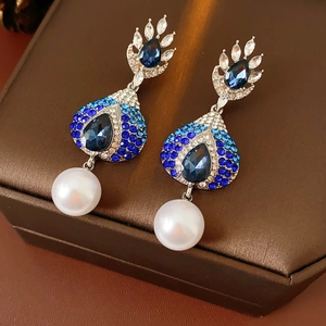 Dettaglio macro di orecchini vintage con perle e cristalli blu su metallo argento