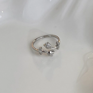 Close-up of silver tulip ring with micro-pave crystals on white wave texture