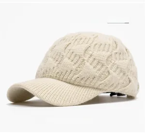 Detail of beige cable knit baseball cap showing textured thick yarn and ribbed brim style