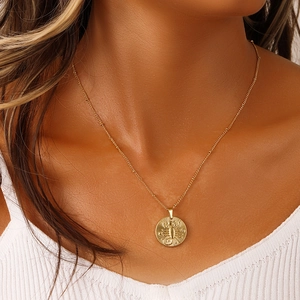 Detailed close-up of gold coin pendant with embossed Scorpio zodiac sign on necklace