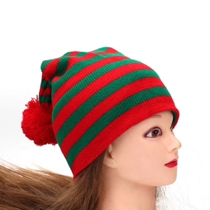 Détail du bonnet de Noël tricoté à rayures rouges et vertes avec pompon rouge vif