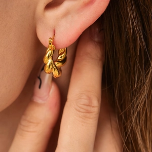 Polished 18k gold plated titanium steel twisted hoop earrings worn by a model