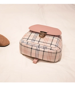 Close-up of the gold metal clasp on a pink and checkered mini backpack with fine stitching