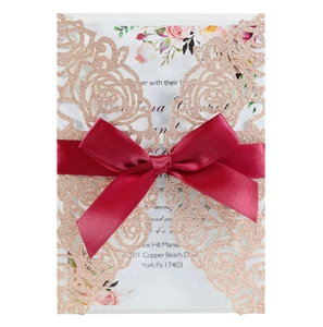 Laser-cut rose gold glitter wedding invitation with floral insert and burgundy ribbon
