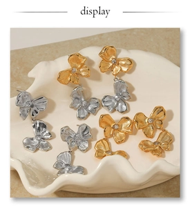 Close-up of bow knot earrings with brushed metal texture and zircon inlay in a ceramic dish