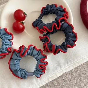 Denim scrunchies with red scalloped edges and plastic clasp on a white plate