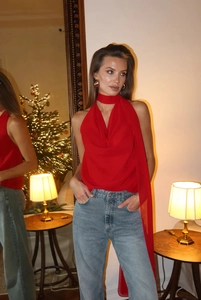 Detailansicht eines roten ärmellosen Neckholder-Tops kombiniert mit blauen Jeans im Raum