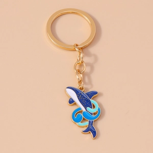 Vue détaillée du porte-clés baleine en métal doré avec émail bleu et paillettes
