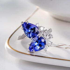 Luxurious open ring featuring two pear-cut blue tanzanite stones and sparkling diamonds