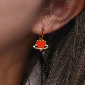 Detailed view of a gold heart planet earring with red enamel and sparkling zircons