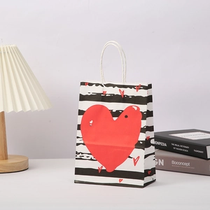 Black and white striped paper gift bag with red hearts and white rope handles