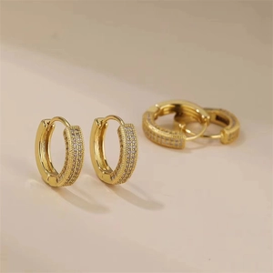 Boucles d'oreilles créoles dorées avec pavé de cristaux sur fond beige