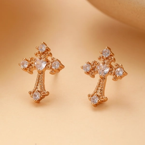 Macro shot of gold cross stud earrings with heart-shaped white zircon and milgrain detail