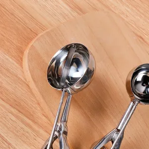 Stainless steel ice cream scoop with mechanical lever on a rustic wooden tray