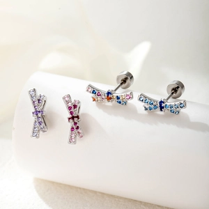 Silver bow and dragonfly earrings with purple and colorful cubic zirconia on white stands