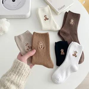 Détail de chaussettes en coton côtelé avec broderie d'ours dans des tons terreux