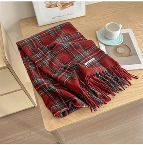 Detail of red vintage plaid scarf with classic fringe tassels on a wooden tabletop