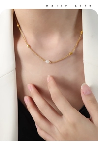 Detail of a minimalist gold-plated necklace featuring a freshwater pearl on a model