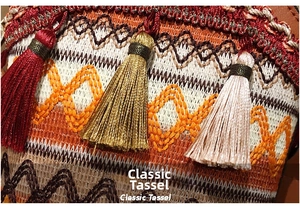 Macro shot of ethnic woven bucket bag featuring multicolor tassels and detailed embroidery