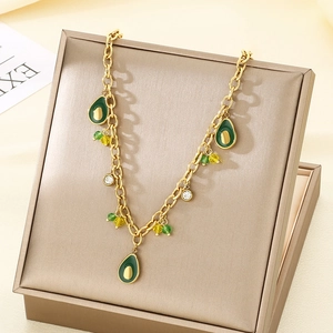 Gold chain necklace with avocado pendants and green beads on a jewelry box lid