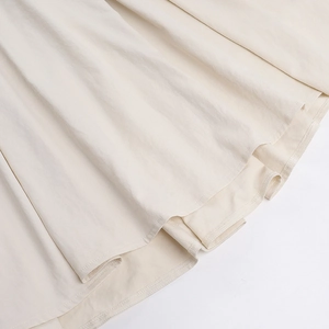 Gros plan détaillé de l'ourlet de la robe beige clair montrant la couture et la texture