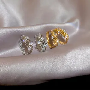 Lava texture irregular rings with sparkling zircons on elegant pink satin background