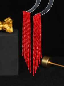 Close-up of elegant long red rhinestone tassel earrings with a shimmering draped finish