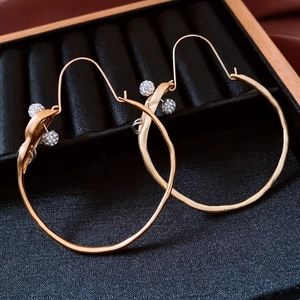 Detail of twisted gold-finish hoop earrings with sparkling crystal-encrusted spheres