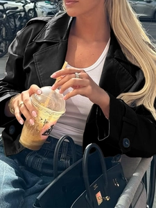 Detail einer schwarzen Kurzjacke mit Knopfmanschetten in einem Outdoor-Café-Ambiente