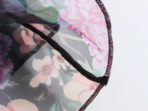 Detail von rosa floralem Organza-Stoff mit schwarzer Paspelierung an einem Damen-Oberteil