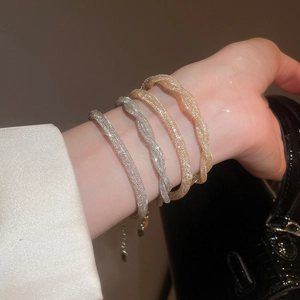 Close-up of four gold and silver twisted mesh bracelets featuring a sparkling diamond effect