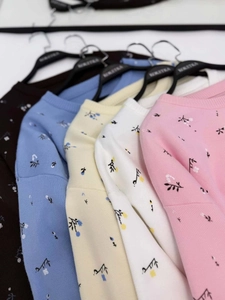 Detail showing knit texture and floral patterns on round neck sweaters in five colors