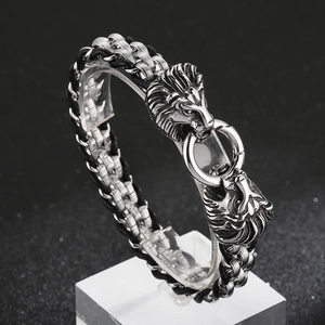 Detail of dual lion head clasp on a black and silver braided men's leather bracelet