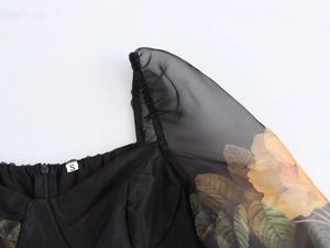 Détail du col carré et des manches en organza à fleurs sur cette robe noire