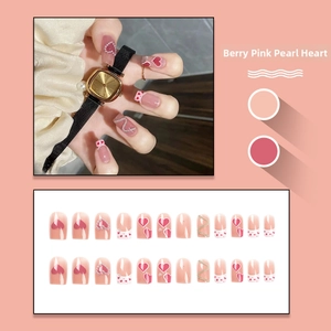 Detail of pink press-on nails with pearl accents, heart patterns, and silver chains