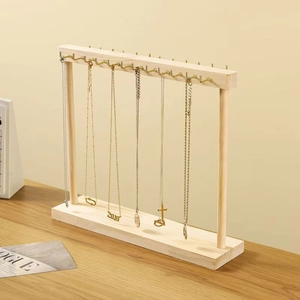 Detail of wooden necklace organizer with gold hooks and stable base on wooden desk