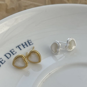 Close-up of gold and silver heart studs with mother of pearl inlay on white tray