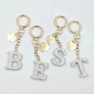 Detailed view of rhinestone BEST alphabet keychain set with heart pendants on white background