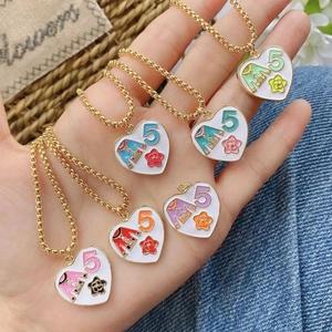 Detail of diverse enamel heart pendants with flower and number five on gold chains
