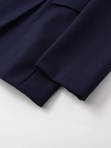 Dettaglio della manica del blazer blu navy che mostra il tessuto a trama e le cuciture fini