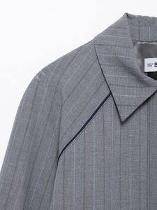 Detail of grey striped blazer showing notch lapel and dark blue piping on the shoulder seam