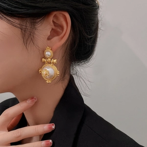 Close-up of model wearing gold vintage flower pearl hoop earrings in retro style
