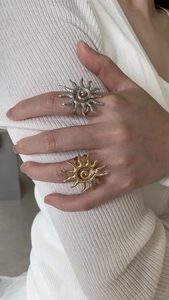 Detail view of stacked gold and silver sun-shaped spiral rings on a model's hand