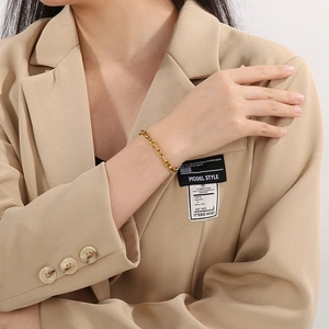 Goldenes Edelstahl-Armband mit Schweinenasen-Gliedern am Handgelenk des Models