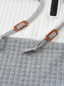 Detail of hoodie chest area with textured grid pattern and brown leather drawstring toggles