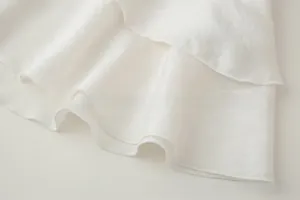 Detailed macro view of white tiered ruffle layers with fine overlock stitching edges
