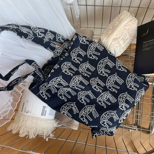 Detail of navy canvas tote bag with white animal embroidery in a shopping cart